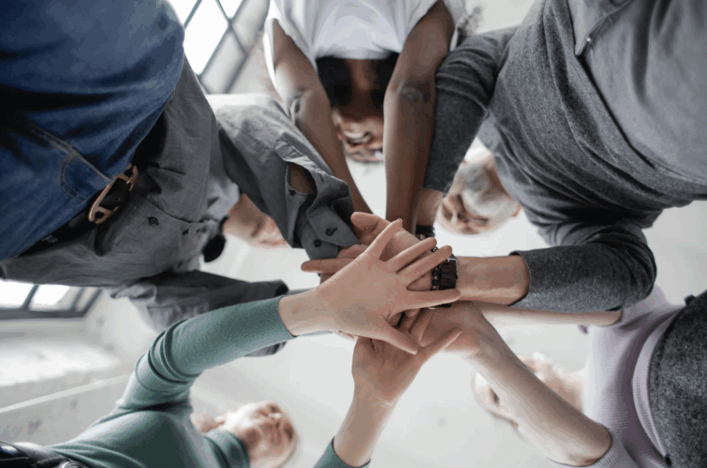 Group of people in a circle with their hands in the middle
